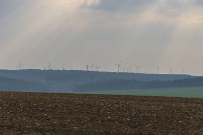 Wind turbines on field against sky