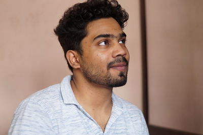 Young man looking away against wall