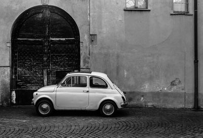 Side view of old car on street against building