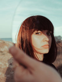 Portrait of young woman reflecting on mirror at beach against sky