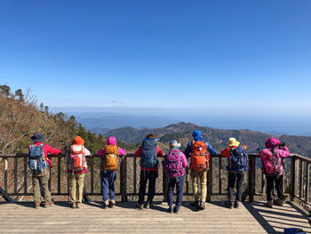 Rear view of people on mountain against clear blue sky