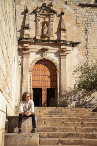 Mexican with curly hair, sitted on staircase, outside baroque temple