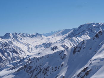 Scenic view of snowcapped mountains against clear blue sky