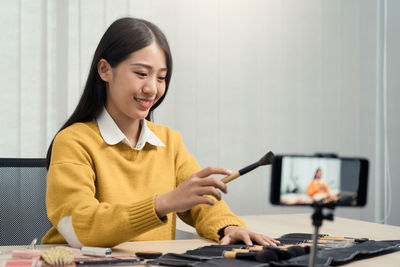 Young woman using mobile phone while sitting at home