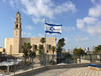 Flag by building against sky franciscan church of the annunciation