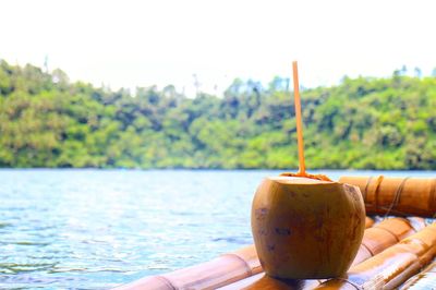 Close-up of hand holding drink against water