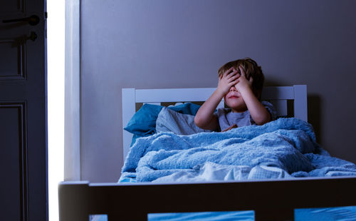 Young woman sitting on bed at home