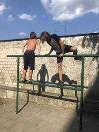 Rear view of friends standing on railing against sky