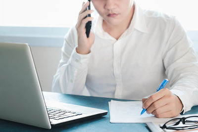 Midsection of man using laptop on table