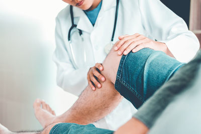 Midsection of doctor examining patient leg at hospital