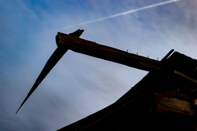 Low angle view of bird perching on roof against sky