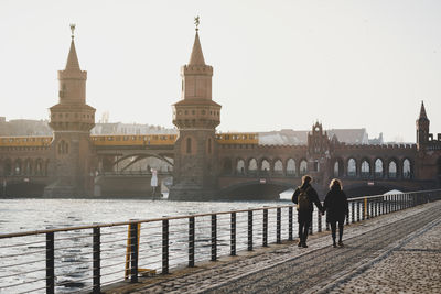 People on bridge over river in city