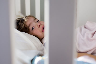 Portrait of baby girl crying while lying in crib at home