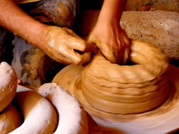 Cropped hands of person working on pottery wheel