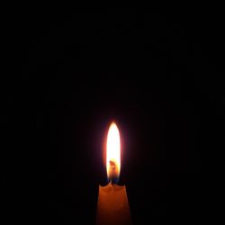 Close-up of illuminated candle in darkroom