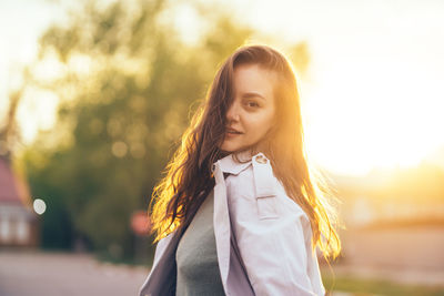 Beautiful girl with long hair in a grey trench coat outdoors on the street spring