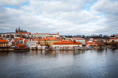 River by city against cloudy sky