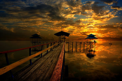 Silhouette pier on beach against sky during sunset