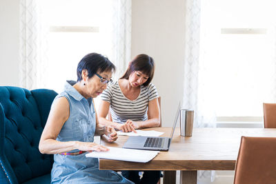 Female friends using laptop at home