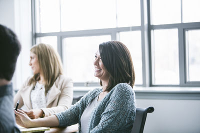 Business people smiling while sitting in meeting at board room