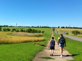 Rear view of children on agricultural field against sky