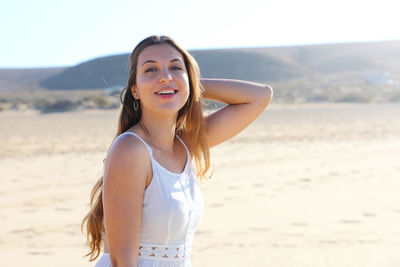 Smiling young woman looking away while standing at beach