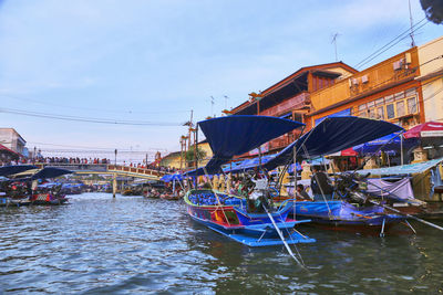 Boats moored at harbor against sky