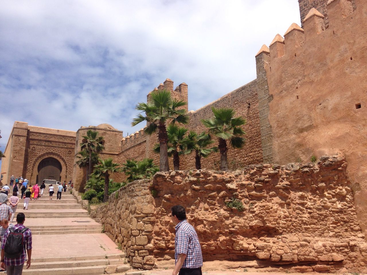 architecture, built structure, building exterior, lifestyles, sky, leisure activity, men, person, walking, full length, cloud - sky, casual clothing, rear view, standing, steps, history, cloud, stone wall