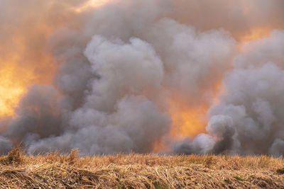 Panoramic view of bonfire on field against cloudy sky