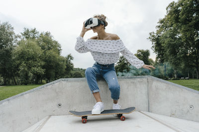Young woman with skateboard wearing vr glasses in a skatepark