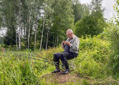 Side view of a man sitting on grassland