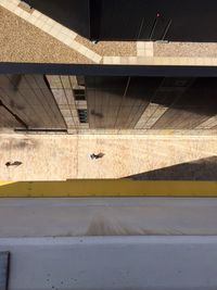 High angle view of person walking on road amidst buildings during sunny day