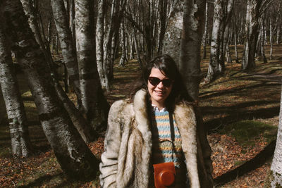 Portrait of smiling young woman standing in forest