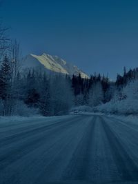 Road by snowcapped mountain against sky