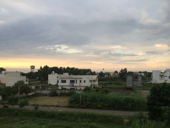 Houses against cloudy sky at sunset