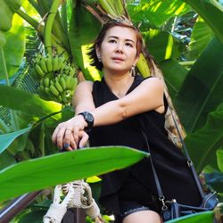 Low angle view of mature woman looking away while standing amidst trees