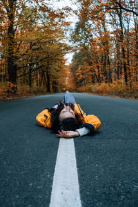 Confidence woman lying on the road with autumn tree around. new life, path choice, ambition