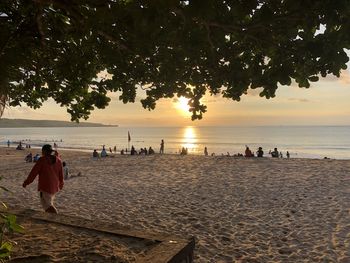 People on beach against sky during sunset