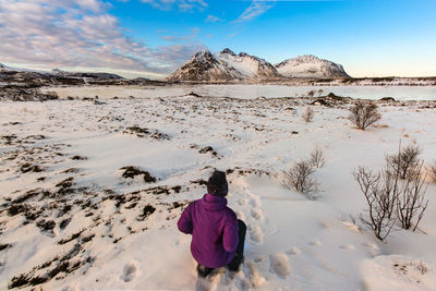 Rear view of person on snowcapped mountain against sky