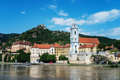 Buildings by river against sky