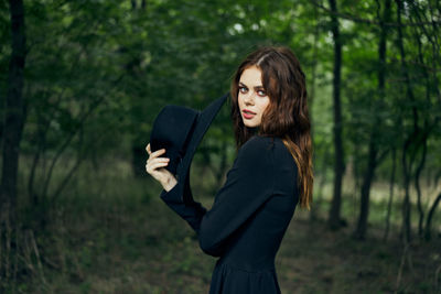 Young woman using mobile phone while standing in forest