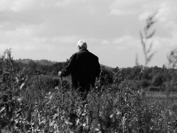 Rear view of man standing on land against sky