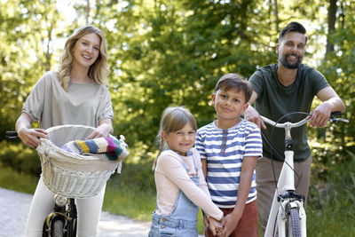 Portrait of smiling friends riding bicycles in park