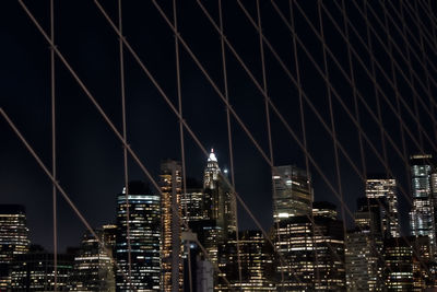 Illuminated modern buildings in city against sky at night