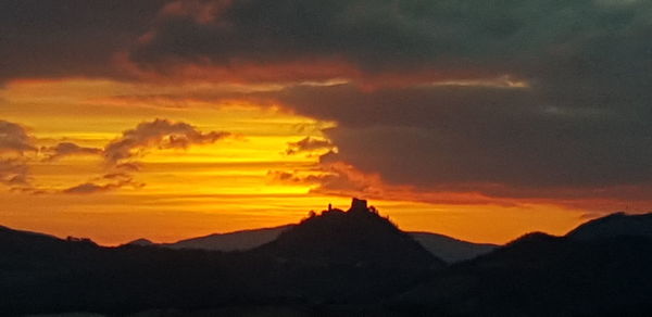 Scenic view of silhouette mountains against orange sky