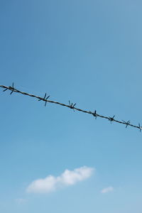 Low angle view of barbed wire fence against sky