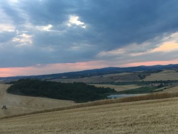 Scenic view of agricultural field against sky during sunset