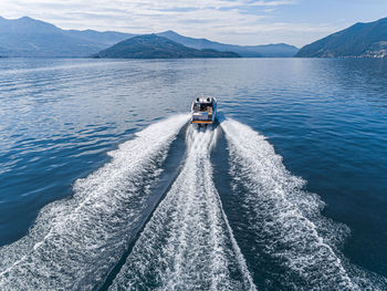 Boat sailing on sea by mountain against sky