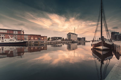 Boats moored in harbor at sunset