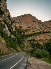 Road leading towards mountains against sky